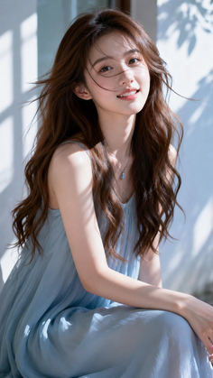 Woman with long brown hair in a blue dress, smiling outdoors with dappled sunlight