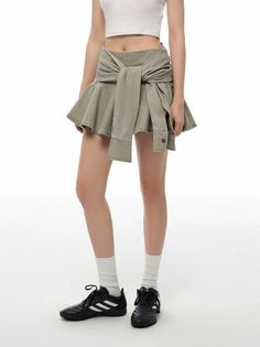 Person in a white crop top and mini skirt with a shirt tied around the waist