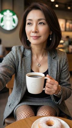 Woman in a gray blazer and fishnet stockings holding a coffee cup