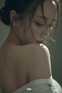 Woman with bare shoulders and dark hair in an updo, looking down