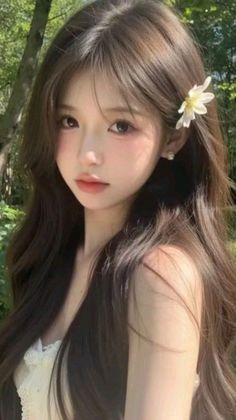 Woman with long brown hair and a white flower in her hair outdoors