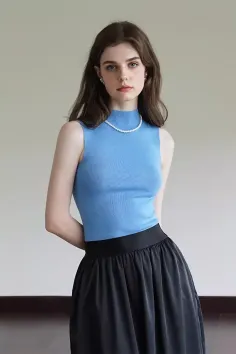 Woman with long brown hair wearing a blue top and black skirt with a pearl necklace