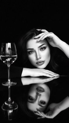 Woman with long hair and a wine glass, reflected on a dark surface