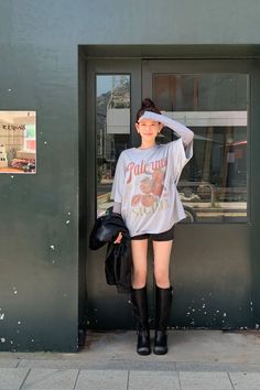Woman in an oversized t-shirt and black shorts with knee-high boots outdoors
