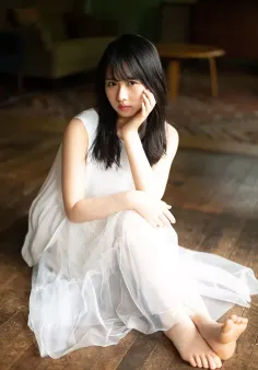 Woman in a white dress sitting on a wooden floor indoors