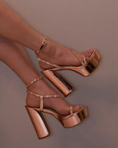 Feet wearing rose gold platform high heels with sparkling straps