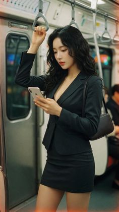 Woman in a black suit and mini skirt on a subway train, holding a phone