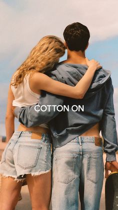 Couple embracing from behind, wearing denim and a hoodie outdoors