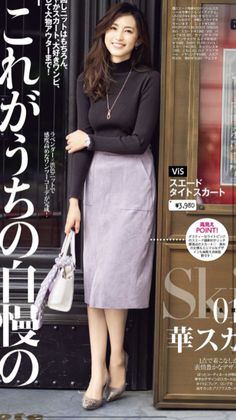 Woman in a black turtleneck and lavender pencil skirt holding a white handbag