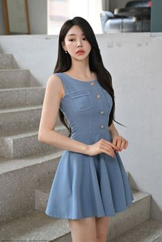 Woman in a light blue sleeveless dress standing indoors