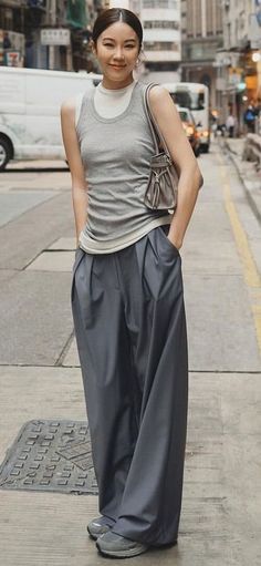 Woman in a grey sleeveless top and wide leg pants on a city street