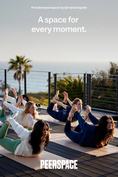 Multiple women doing yoga in bow pose on an outdoor deck with an ocean view