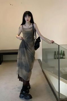 Woman with long black hair wearing a slip dress and chunky shoes indoors