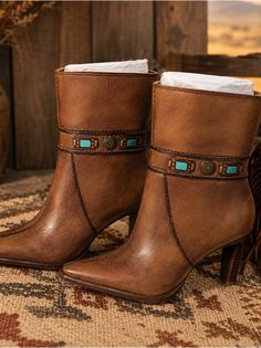 Pair of brown leather ankle boots with turquoise and metal accents on a patterned rug