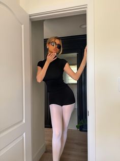 Woman in black top and white tights posing in a doorway
