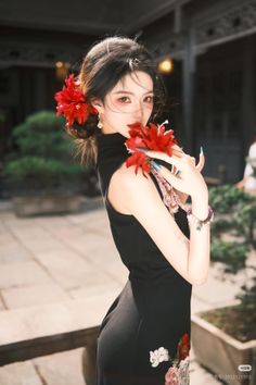 Woman in a black dress with red flowers in her hair and hands outdoors