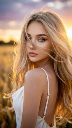 Woman with blonde hair in a white dress looking over her shoulder at golden hour