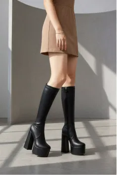 Person wearing a mini skirt and black platform knee-high boots