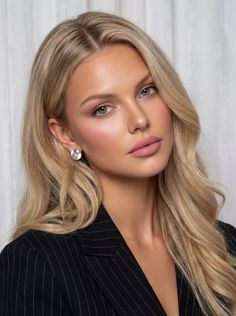 Blonde woman with long hair wearing a pinstripe suit and earrings