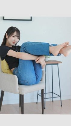 Woman with long hair in blue jeans and a black t-shirt sitting on a chair indoors