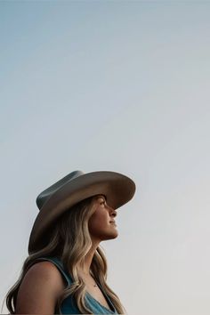 Woman in a cowboy hat looking up against a clear sky