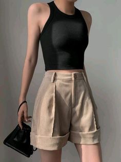 Person in a black tank top and beige corduroy shorts holding a black handbag