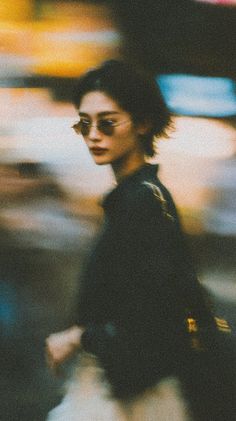 Woman with short hair and sunglasses on a blurry street with film grain