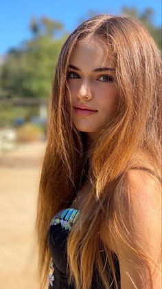 Woman with long hair and blue eyes wearing a black top outdoors