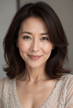 Woman with short brown hair wearing a lace top, smiling at the camera