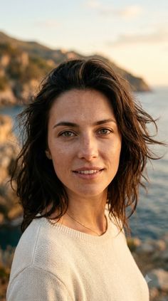 Woman with short hair and freckles outdoors by the ocean at golden hour