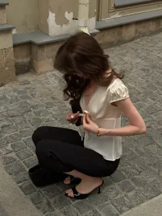 Woman with long brown hair crouching on a cobblestone street