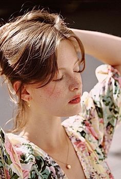 Woman with freckles and closed eyes wearing a floral dress