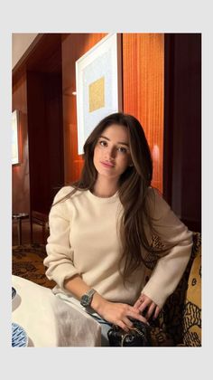 Woman with long dark hair wearing a cream sweater indoors