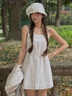 Woman in a white dress and hat with braided hair in a park