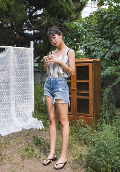 Woman in denim shorts and a striped top posing outdoors
