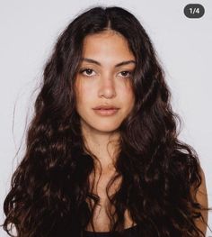 Woman with long wavy dark hair in a studio portrait with a white background