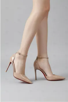 Pair of nude high heels with ankle straps and red soles on slim legs