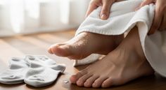 Person drying wet feet with a white towel on a wooden floor