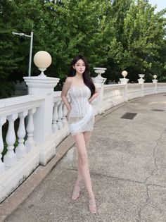 Woman in a white lace strapless dress and high heels outdoors
