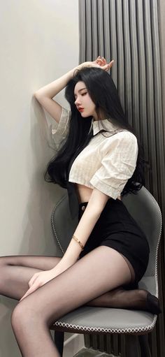 Woman with long black hair wearing a crop top and black shorts with pantyhose