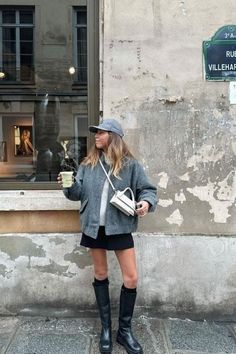 Woman in a baseball cap, jacket, mini skirt, and boots on a street