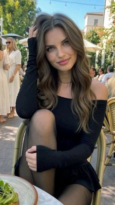 Woman with long hair in a black top sitting outdoors