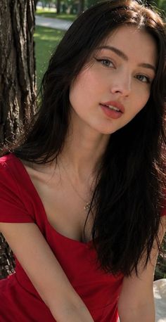 Woman with long dark hair in a red dress outdoors with soft lighting