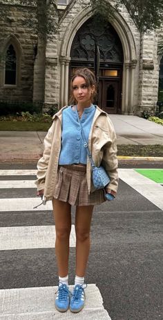 Woman in a plaid skirt and blue cardigan standing on a crosswalk