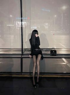 Woman with long black hair in a black dress and tights at night