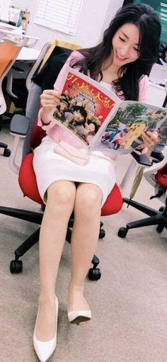 Woman with long dark hair in a pink shirt and white skirt reading a magazine