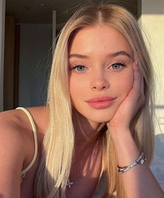 Blonde woman with blue eyes and jewelry in soft, warm lighting