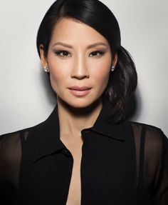 Woman with black hair and a black sheer-sleeved shirt looking at the camera