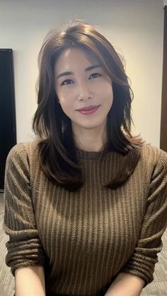 Woman with long brown hair wearing a brown ribbed sweater indoors