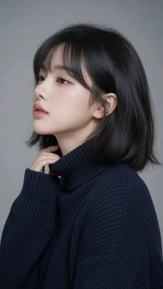 Woman with short black hair wearing a dark turtleneck sweater in a studio setting